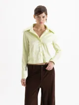 Camisa de jacquard con diseño de flores sutiles, color blanco, con cuello amplio de puntas marcadas, mangas largas con puños y cierre frontal con botones.