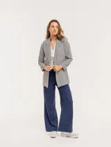 Pantalón de lino color beige, de tiro alto, pierna ancha y levemente acampanada. Tiene pinzas delanteras, elástico en la pretina trasera, cierre delantero y broche interno, bolsillos laterales y dobladillo invisible.