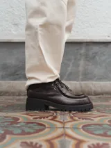 Bota marrón de cuero con textura de cocodrilo, cordones y suela track.