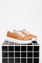 Championes acordonados de cuero color caramelo con suela blanca.