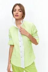 Camisa de manga larga confeccionada en broderie de algodón con bordado en hilo color amarillo flúo. Presenta cuello mao, cartera frontal con volados y puños con detalles de volados en color blanco.