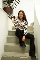Saco de punto con diseño combinado de estampado animal print en el cuerpo y rayas horizontales en las mangas. Presenta cuello redondo, cierre frontal con botones y terminaciones en tejido acanalado negro.