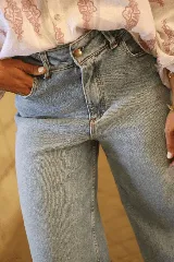 Jean de corte recto y tiro alto, confeccionado en denim de tono azul claro con acabado lavado. Presenta cierre frontal con botón metálico y bolsillos laterales.