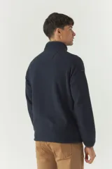 Campera polar gris de poliéster con cuello elevado, cierre frontal, bolsillos laterales con cierre y logo estampado en el pecho.