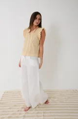 Camisa sin mangas de voile de algodón color amarillo maíz con detalles broderie, cuello mao y volados en los hombros. Cuenta con cierre frontal de botones y diseño romántico.