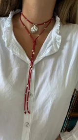 Collar de cuero azul con dije plateado en forma de caracol y detalles de cuentas plateadas. El collar tiene dos tiras que caen por el frente.