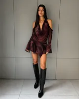 Conjunto de dos piezas compuesto por un top halter con escote drapeado y mangas largas separadas con diseño acampanado, y una minifalda tableada de tiro bajo. Ambas prendas presentan un estampado abstracto en tonos marrones y negros con efecto traslúcido.