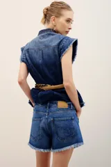 Short de denim azul medio con diseño de cinco bolsillos, cierre frontal con botones y bordes desmechados en el ruedo.
