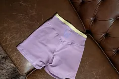 Calza corta deportiva tiro alto, color lila con pretina ancha de contraste en color verde lima.