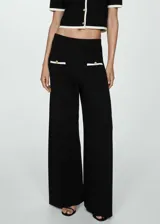Pantalon de punto fino color negro, de corte recto y tiro medio. Presenta cintura elástica, dos bolsillos delanteros con ribete en contraste color blanco y botones decorativos dorados.
