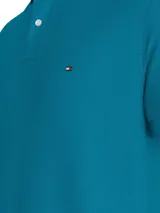 Chomba azul de Tommy Hilfiger, modelo 1985, de corte regular, con cuello tipo chomba, cartera de dos botones, logo bordado en el pecho y detalles distintivos de la marca. Confeccionada en mezcla de algodón y poliéster.