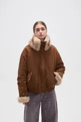 Campera de piel sintética en tono tostado, con cuello alto, cierre frontal y diseño holgado.