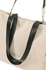 Cartera tipo shopper color negro, confeccionada en poliuretano, con bolsillos laterales con cierre y correa larga ajustable.