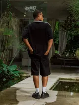 Bermuda negra de gabardina, corte ancho y largo, con bolsillos laterales.