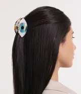 Pinza para el pelo de tamaño mediano con diseño en forma de ojo. Presenta un estampado de iris azul sobre fondo blanco y detalles en carey en los bordes.