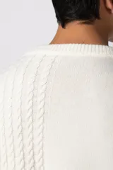 Sweater de punto color blanco con diseño de textura combinada, presentando un lado liso y otro con tejido trenzado. Posee cuello redondo, mangas largas y un corte relajado.