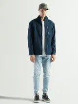 Campera azul marino de poliéster, tipo softshell, con cuello alto y cierre frontal. Cuenta con bolsillos laterales con cierre y un bolsillo vertical en el pecho. No tiene capucha.