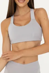 Top deportivo gris claro de poliéster y elastano, con espalda descubierta, breteles finos y banda elástica inferior.