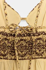 Vestido midi de broderie en tonos mostaza y marrón, con escote en V, tirantes finos ajustables, abertura cut-out en la cintura y espalda con nido de abeja elástico.