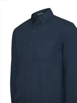Camisa de manga larga para hombre, teñida en prenda con efecto degradado (ombre) en tonos azules. Confeccionada en popelina de algodón orgánico, presenta un bolsillo en el pecho con logo bordado y mangas ajustables con botón. El ruedo es redondeado.