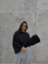 Conjunto deportivo compuesto por un buzo negro de corte cropped con costuras a la vista y un pantalón jogging gris de tiro alto, corte holgado y costuras verticales decorativas.