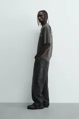 Camiseta de manga corta y cuello redondo, color gris oscuro o negro deslavado, con estampado de texto en blanco en el pecho.