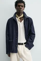 Cazadora de denim de algodón azul marino oscuro, corte regular fit, con cuello solapa, bolsillos frontales de plastrón y cierre de botonadura frontal.
