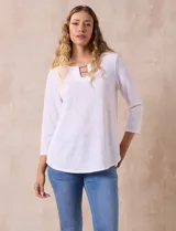 Blusa blanca de tejido labrado con cuello redondo, escote en V y aplique metálico.
