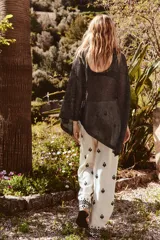 Pantalón color crema de tiro medio con cintura elástica ajustable y bolsillos delanteros. Presenta bordados florales en negro y corte ancho.