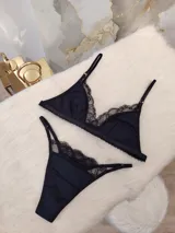 Conjunto de lencería compuesto por un corpiño triangular y una bombacha, ambos confeccionados en algodón negro con detalles de encaje en los bordes. El corpiño cuenta con breteles regulables y la bombacha presenta un diseño con tiras laterales.