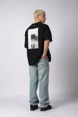 Remera oversize de algodón 100% premium, color blanco hueso, con bordado frontal "90's" en negro y un parche trasero con una imagen estilo videoclip de Nirvana.