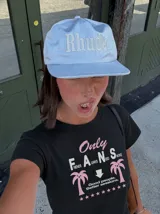 Remera blanca de manga corta, con cuello redondo y diseño gráfico estampado en el pecho que incluye texto y palmeras.