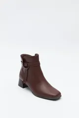 Bota corta de caña baja color negro, con puntera cuadrada, taco medio y tira decorativa con hebilla metálica en el lateral.