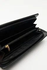 Billetera de mano con textura efecto cocodrilo, color beige, con cierre perimetral y tira de muñeca desmontable.