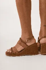 Sandalia de taco chino y plataforma forrada, color tostado, con doble tira ancha en el empeine con detalles de costuras y pespuntes artesanales. Cuenta con tira ajustable con hebilla en el talón.