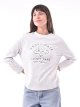 Remera de manga larga color blanco hueso con cuello redondo y estampado frontal en negro que dice "MESSY HAIR I DON'T CARE LOOKS FABULOUS" junto a un dibujo de un caniche con gafas de sol.