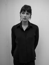 Camisa de manga larga con calce entallado y cartera frontal oculta. Presenta un diseño de superficie lisa con caída suave que se ajusta a la silueta.