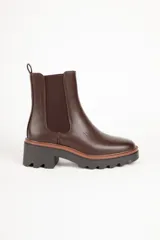 Bota marrón de cuero sintético, estilo Chelsea, con punta redonda, pieza elastizada en los laterales y suela tipo tractor de 6cm de alto.