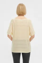 Remera de manga corta de acrílico en color amarillo, con diseño calado, corte holgado y cuello bote.