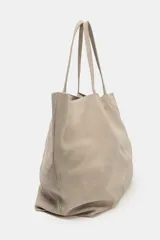 Bolso tipo maxi shopper confeccionado en serraje, con diseño minimalista y doble asa de hombro. Cuenta con un compartimento principal amplio y un bolsillo interior con cierre.