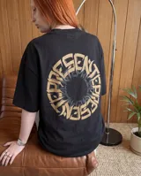 Remera negra de corte oversize, con estampa circular en la espalda que presenta la palabra 'Presente' en tipografía gótica de color beige.