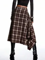 Pollera midi de diseño asimétrico con cruce frontal, confeccionada en tejido fluido con estampado escocés en tonos marrones y beige.