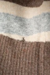 Polera de tejido de punto con diseño a rayas horizontales en tonos marrón, beige y gris. Presenta cuello alto, mangas largas con puños anchos y un corte holgado.