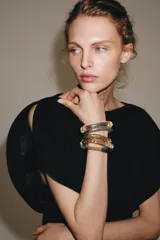 Pack de cinco pulseras elásticas con diseño apilable, compuestas por una combinación de piezas metálicas en tonos dorados, plateados y oscuros con texturas variadas.