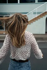 Blusa de escote en pico con volantes frontales, manga larga con puños elásticos y cierre frontal con botones.