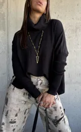 Sweater negro de punto con cuello polera, mangas largas con puños ajustados y diseño holgado.