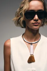 Collar choker metálico plateado con un colgante compuesto por una pieza cilíndrica de resina rosa y una pieza irregular de resina marrón ámbar.