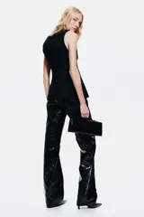 Chaleco largo negro con cuello redondo y cierre de botones frontales. Diseño entallado con bolsillos delanteros ribeteados y abertura en la parte trasera.