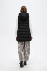 Chaleco acolchado negro con capucha ajustable mediante cordones, cierre frontal con botones a presión y bolsillos laterales con cierre.