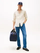 Camisa de manga larga color beige claro, corte slim fit, con cuello abotonado, cierre con botones y logo de Tommy Hilfiger bordado en el pecho.